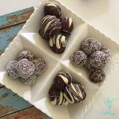 four chocolate covered desserts are arranged on a square plate