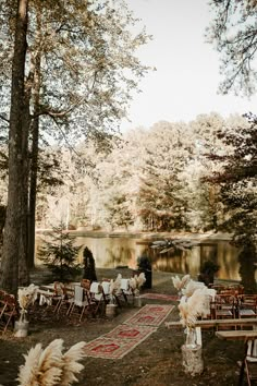 an outdoor wedding venue set up with chairs and rugs in front of the lake