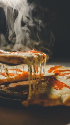 the pizza is being served with hot sauce on it's side and steam coming out