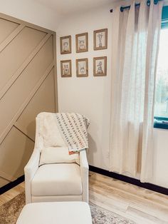 a white chair sitting in front of a window next to a wall with pictures on it