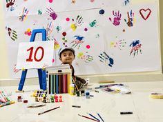 a little boy sitting at a table with lots of art supplies