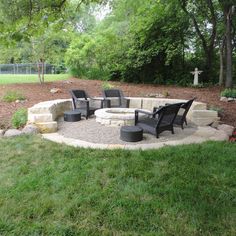 an outdoor fire pit surrounded by chairs