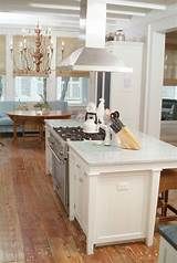 a kitchen with an island, stove top and dining room table in the back ground