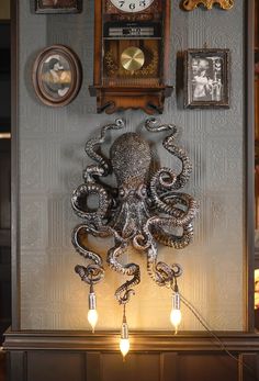 an octopus clock mounted to the side of a wall next to two lamps and framed pictures