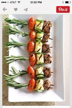 several skewered vegetables are arranged on a white plate with green garnish