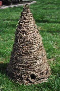 a birdhouse made out of straw sitting in the grass