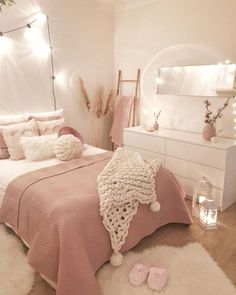 a bedroom decorated in pink and white with lights on the wall, bedding and rugs