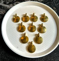 nine gold - plated pendants are on a white plate