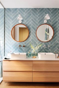 two mirrors on the wall in a bathroom with wooden cabinets and double sinks, along with blue tiles