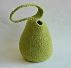 a small green vase with a handle on it's end, sitting on a white surface