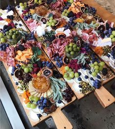 an assortment of fruits and cheeses are arranged on wooden boards