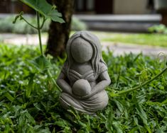 a small buddha statue sitting in the grass