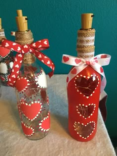 three bottles with hearts painted on them sitting on a table