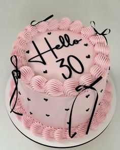 a pink cake with black writing on it that says hello 30 and is decorated with hearts