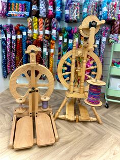 two wooden spinnings sitting on top of each other in front of yarn and scissors