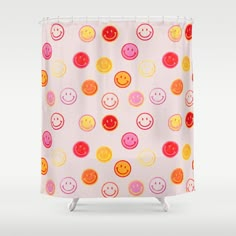 a colorful shower curtain with smiley faces on it's pink and yellow background,