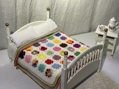 a crocheted blanket on top of a bed with white headboard and foot board