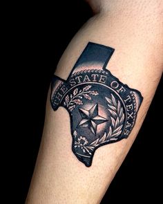 the state of texas tattoo is shown in black and grey ink with an emblem on it