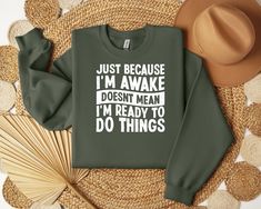 a green sweatshirt that says just because i'm awake doesn't mean i'm ready to do things