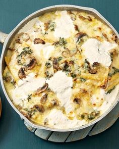 a casserole dish with cheese and mushrooms in it on a blue tablecloth