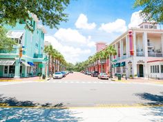 an empty street with cars parked on both sides and palm trees lining the sidewalks in front