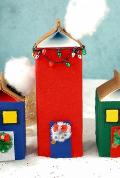 three small houses made out of felt and decorated with christmas decorations are shown in front of a blue wall