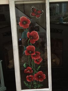 a glass window with red flowers painted on it