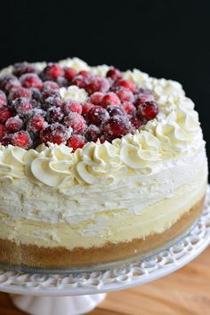 a cake with white frosting and raspberries on top sitting on a plate