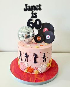 a pink cake with disco balls and vinyl record on top that says, janet is 60