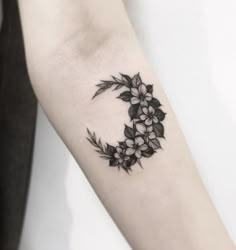 a black and white flowered crescent tattoo on the arm