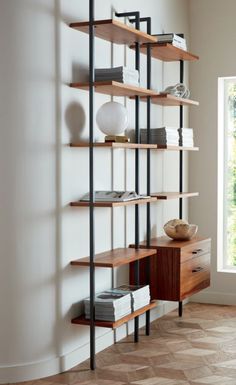 a book shelf with books and other items on it next to a window in a room