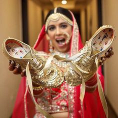 a woman in a red and gold bridal outfit holding two clocks with faces painted on them