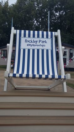 a blue and white striped beach chair sitting in front of a park with rvs