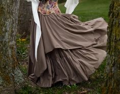 a woman in a dress is standing next to some trees