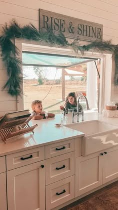 two children are sitting at the kitchen counter in front of an open window that says rise and shine