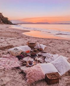 a picnic is set up on the beach at sunset