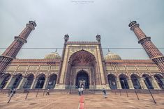 people are standing in front of an ornate building with three tall pillars on each side