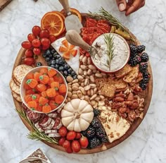 a platter filled with fruit, nuts and crackers on top of a marble table