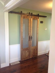 an empty room with two wooden doors and hard wood flooring