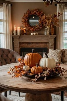 a wooden table topped with pumpkins and greenery next to a fire place filled with candles