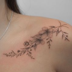 a woman's shoulder with flowers and leaves tattoo on her left side breast area