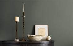 a table with a bowl and two candles on it next to a framed photograph, candle holder and other items