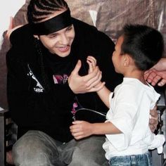 a man sitting next to a little boy in front of a tv screen with his hand on the child's head