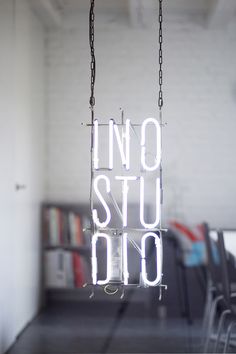 a neon sign hanging from the ceiling in a room with chairs and bookshelves