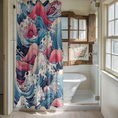 a bathroom with a shower curtain that has an image of waves on it and is next to a bathtub