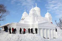 a group of people standing in front of a white building with snow on the ground