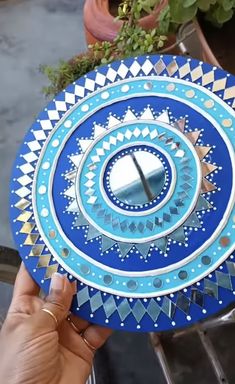 a person holding up a blue and white plate with an intricate design on the side