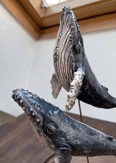 two sculptures of whale tails on top of a wooden table