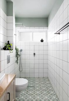 a white tiled bathroom with green flooring and wall tiles in the shower area, along with a wooden countertop