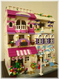 a toy house made out of legos with flowers on the front and side windows